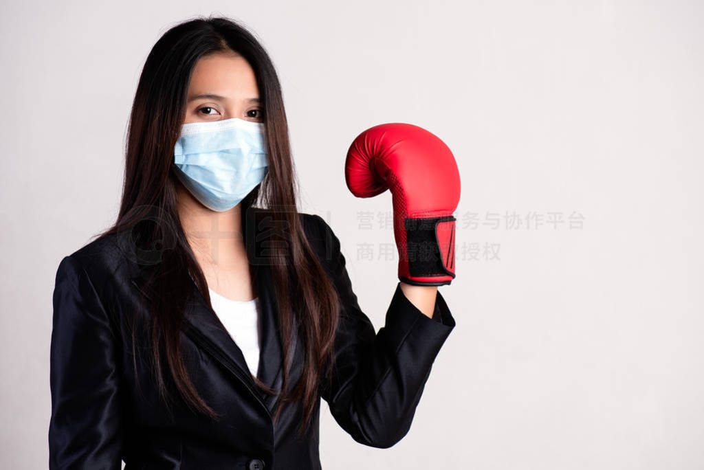 Close up of a businesswoman in a suit wearing red boxing gloves