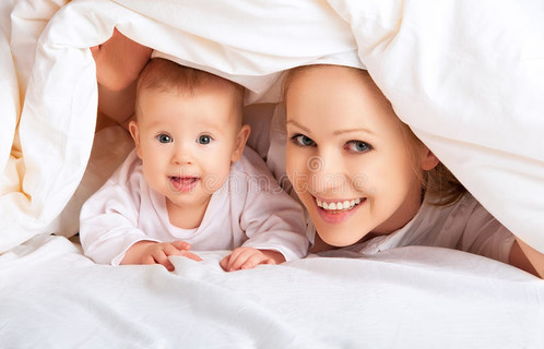 幸福的家庭。母婴在毯子下玩耍