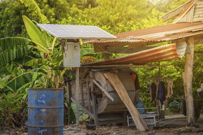 农村住宅区的太阳能电池板和旧油桶准备回收工业 泰国家庭农村风格的农业工业 替代能源概念