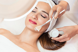 在现代美容中心用<i>保</i><i>湿</i>霜为敏感皮肤进行面部护理时放松美女的脸部特写