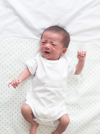 亚洲男婴躺在白床上 哭着肚<i>子</i><i>疼</i>的顶视图