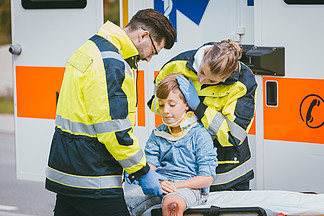 男孩意外受伤 医护人员在救护车前照顾他