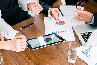 业务 — 银行家 经理或会议专家评估平板电脑上的数字 并比较业务的发展 以提供建议和充当顾问
