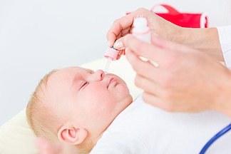 儿科医生在体检时用吸鼻器在鼻孔中涂抹盐水溶液来清理婴儿鼻<i>子</i>的特写