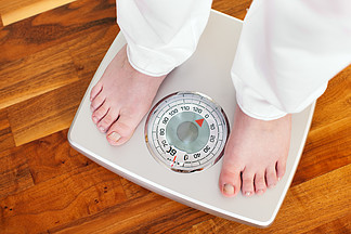 女人（只能看到脚）站在浴室秤上测量体重控制她的节食结果