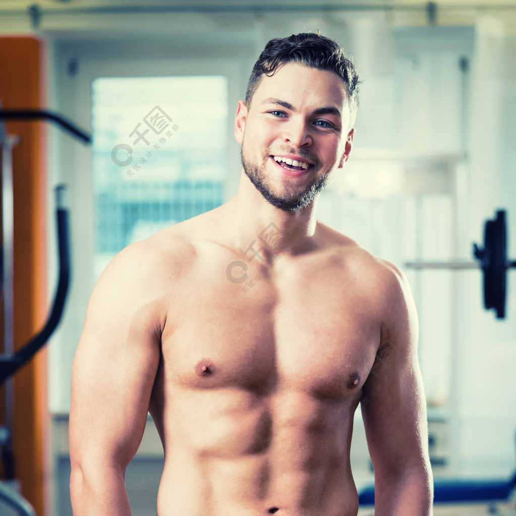 训练有素的运动员在健身俱乐部健身房展示他的肌肉和六块腹肌
