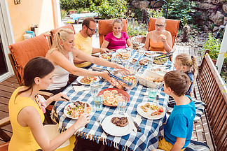 有一个花园聚会的家庭在桌边吃饭 一起享受时光