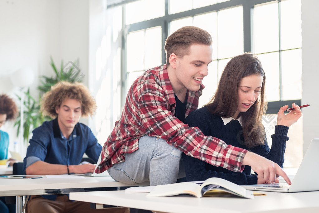 两个欢快的千禧一代学生在现代学院或大学的课堂休息时坐在一起大笑