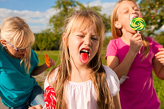 三个吃棒棒<i>糖</i>的女孩 前面的女孩伸出舌头