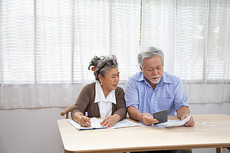 亚洲老年夫<i>妇</i>严重担心计算每月支付的账单或债务 退休老人阅读贷款文件 金钱问题概念