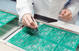 技术人员通过将元件插入生产线上的电<i>路</i>板来组装电子产品