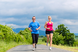 夫<i>妇</i> 男人和女人在乡村街道上慢跑或户外运动健身