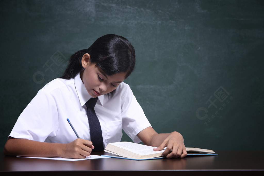 穿制服的女学生在黑板前做作业