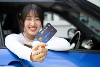 快乐的亚洲年轻女性持有支付卡或信<i>用</i>卡 过去常常在加油站支付汽油 柴油和其他燃料的费<i>用</i> 司机拿着车队卡为汽车加油