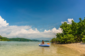 在印度尼西亚田园诗般的旅游目的地度假时 快乐的年轻女子在浅水区划独木舟