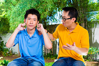 中国亚裔父亲和儿子说话 但他不听 双手捂着耳朵拒绝好的<i>建</i><i>议</i>