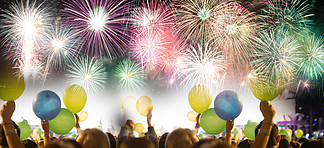 在夜空的抽象彩色烟花背景和<i>欢</i>呼的人群在新年派对节日与手边气球