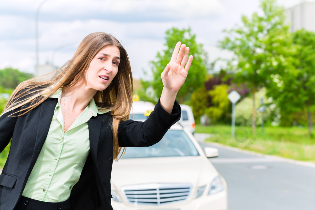 等待出租車的年輕女商人阻止司機在人行道上揮手