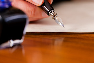 女人（只看到一只手）用钢笔和墨水在纸上写信 <i>前</i><i>景</i>是她有一个墨水罐