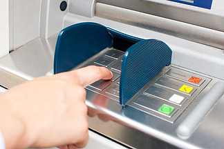 ATM 或自动提款机前的女人正在输入她的 <i>PIN</i> 码