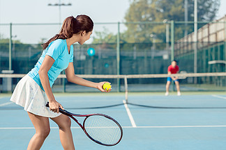 一名职业女球员在网球比赛中发球前拿着球拍和球微笑的侧<i>视</i>图