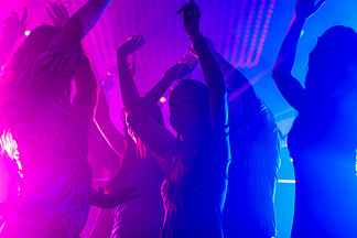 一群派对人士——男人和女人——在迪<i>斯</i>科俱乐部里随着音乐跳舞