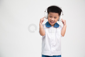 开朗微笑的亚洲小男孩穿着学生制服听音乐 耳机隔离在白色背景 幼儿园第一天和返校概念 泰国男孩模型