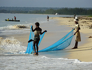 非洲莫桑比克德尔加杜角奔巴岛 Chuiba Bay Lodge 前的海滩上 当地人男人和女人清晨在海洋捕鱼 他们的船和网