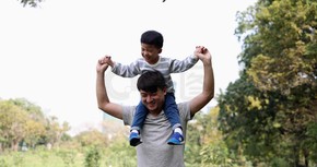 在花园公园里 亚洲小男孩坐在父亲的肩膀上