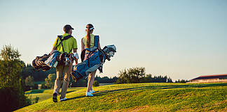 一对幸福的夫妇 <i>穿</i><i>着</i>高尔夫服装 拥有健康的生活方式 在夏日阳光明媚的日子里 带<i>着</i>带专业俱乐部的立袋走向高尔夫球场