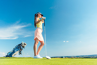 在夏日阳光明媚的日子里 一位身着现代高尔夫服装的健康女性在乡村高尔夫球场的绿色草地上望着地平线的侧<i>视</i>图
