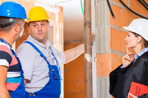 审查员或专家或律师和建筑商或工人 戴着头盔控制建筑或建筑工地 以报告协议中的缺陷或错误或缺陷