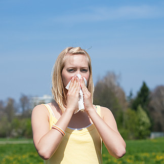 春天 患有流感或过敏症的女人对着她的手帕打<i>喷</i>嚏