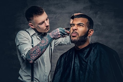 时尚纹身理发师为黑胡子男性理发