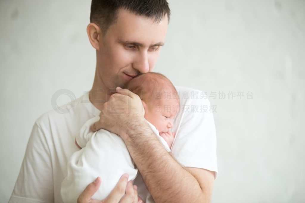 Beb dormido en los brazos de su padre mientras su padre le besa la cabeza