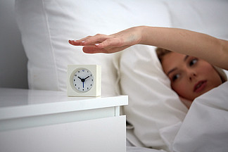 休息，睡觉，<i>时</i>间和人们的观念-关闭关闭闹钟在家里的床卧室里的年轻女子
