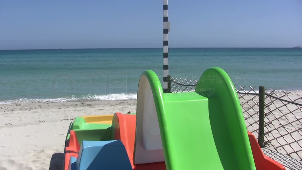 Blick nber den Strand mit einem Spielplatz auf ein blaues Meer hinaus