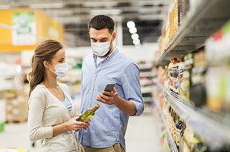 食品购物，消费者至上主义和大<i>流</i>行的概念— —幸福的夫妇戴着脸防护医疗口罩的防护免受病毒病的影响，与在杂货店或超市购买橄榄油的智能手机夫妇在面具与电话和商店的橄榄油