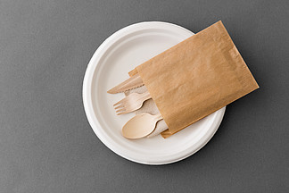 餐具，回收和生态友好的概念-木勺，叉子和刀在纸碟上灰色的背景上木勺，??叉子和刀子在纸碟上