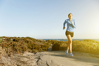 跑步在<i>海</i>滩的体育赛跑者解决适合女性健身模型沿着<i>海</i><i>洋</i>慢跑