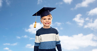 学校，教育和学习观念-学士帽的小男孩或在蓝天和云彩背景的灰<i>泥</i>板小男孩在学士帽或现在的天空