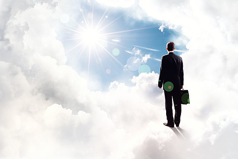 商业上的成功站在云高在天空中的商人的背影