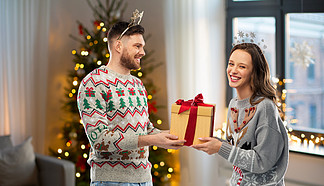 人和假日概念-愉快的加上<i>画</i>象在丑陋的毛线衣<i>党</i>的圣诞节礼物幸福的夫妇，在圣诞毛衣和礼品盒