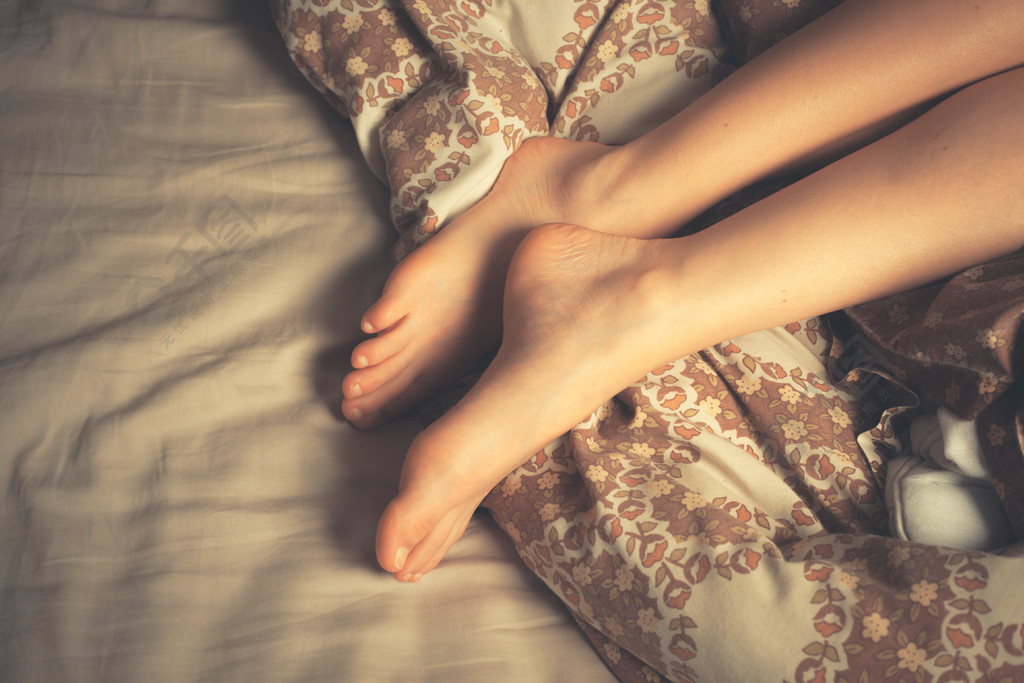 一个美丽的年轻女子躺在床上的双腿