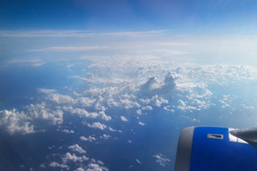 云彩和天空如通过航空器的窗口被看见，飞机的机翼在蓝色和多云的天空