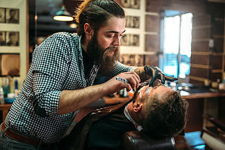 理发师通过在理发店剃刀片来剃去客户的胡<i>须</i>