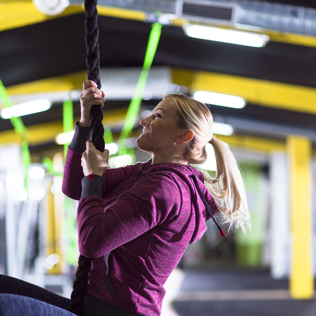 做繩索的年輕肌肉婦女上升在crossfitness健身房女人在做繩子攀爬1年