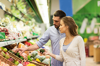 购物，食品，销售，消费主义和人们观念-幸福的夫妇买鳄<i>梨</i>在杂货店或超市