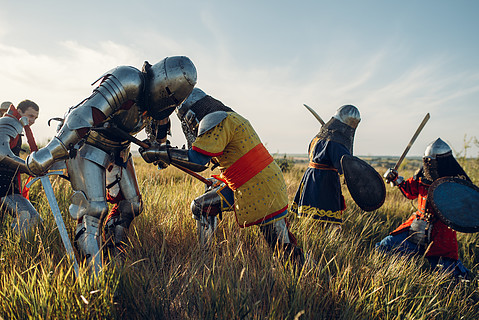 身穿铠甲和头盔的中世纪骑士用剑和斧头作战,这是一场伟大的战斗装甲