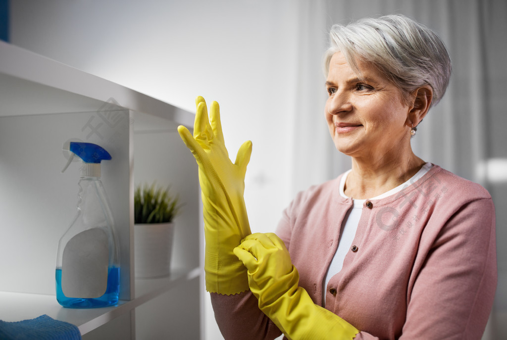 清洁,家务劳动和家务的概念— —防护橡胶手套放在家里的高级女人戴上